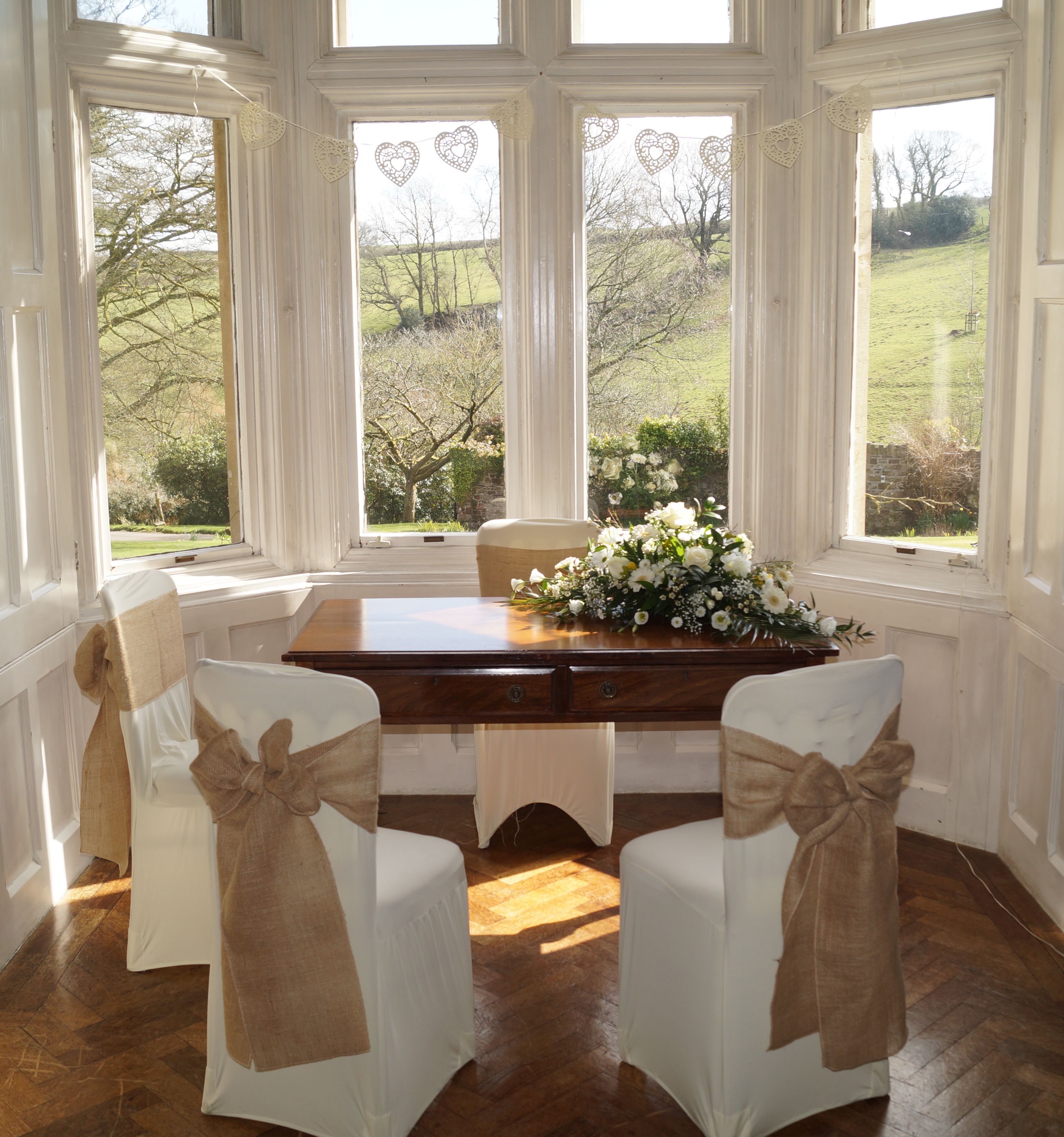 A beautifully decorated signing table set in front of a large bay window with a view of the countryside.