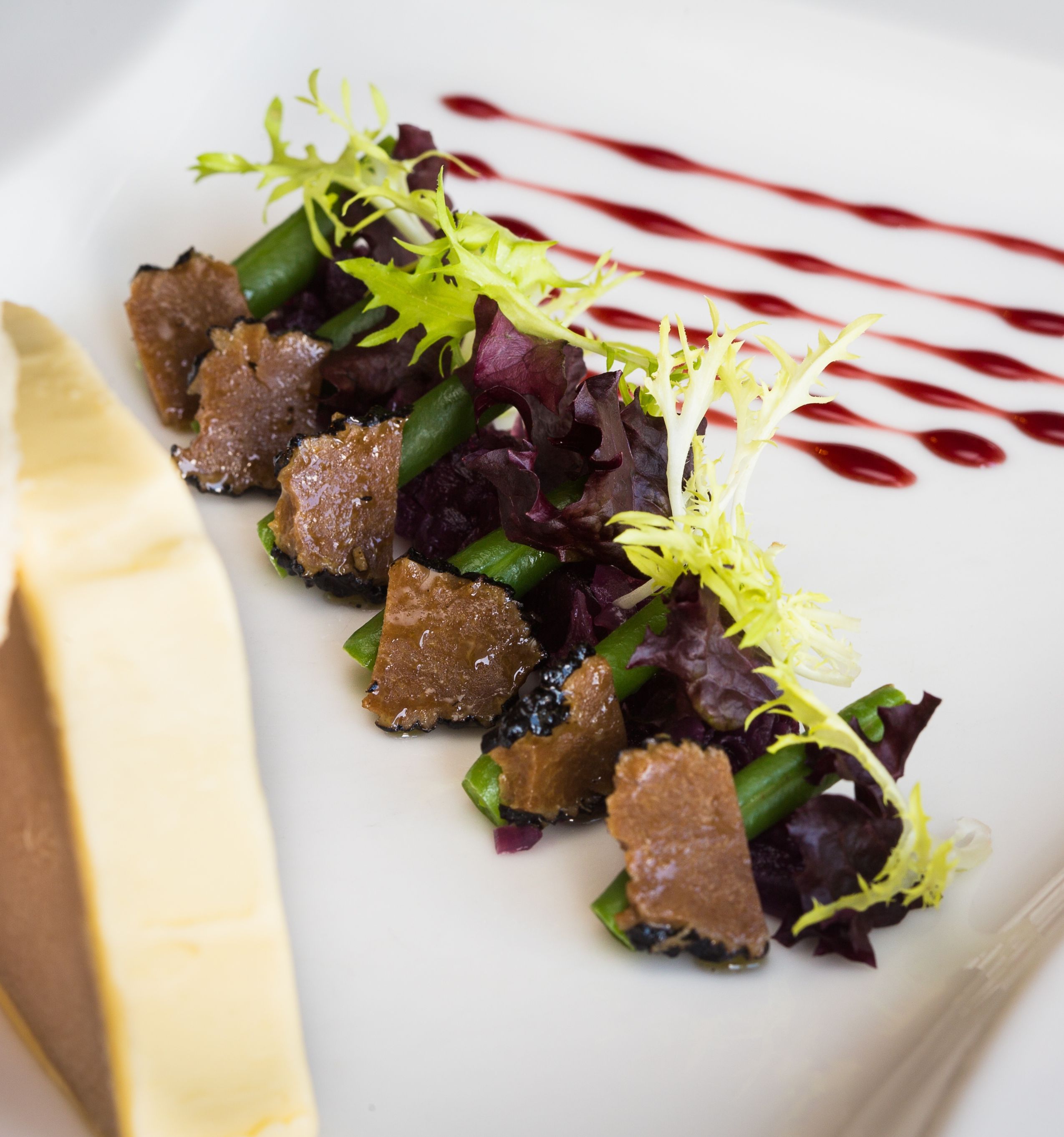Elegant dish of fresh salad with sliced truffles and green beans, garnished with mixed greens