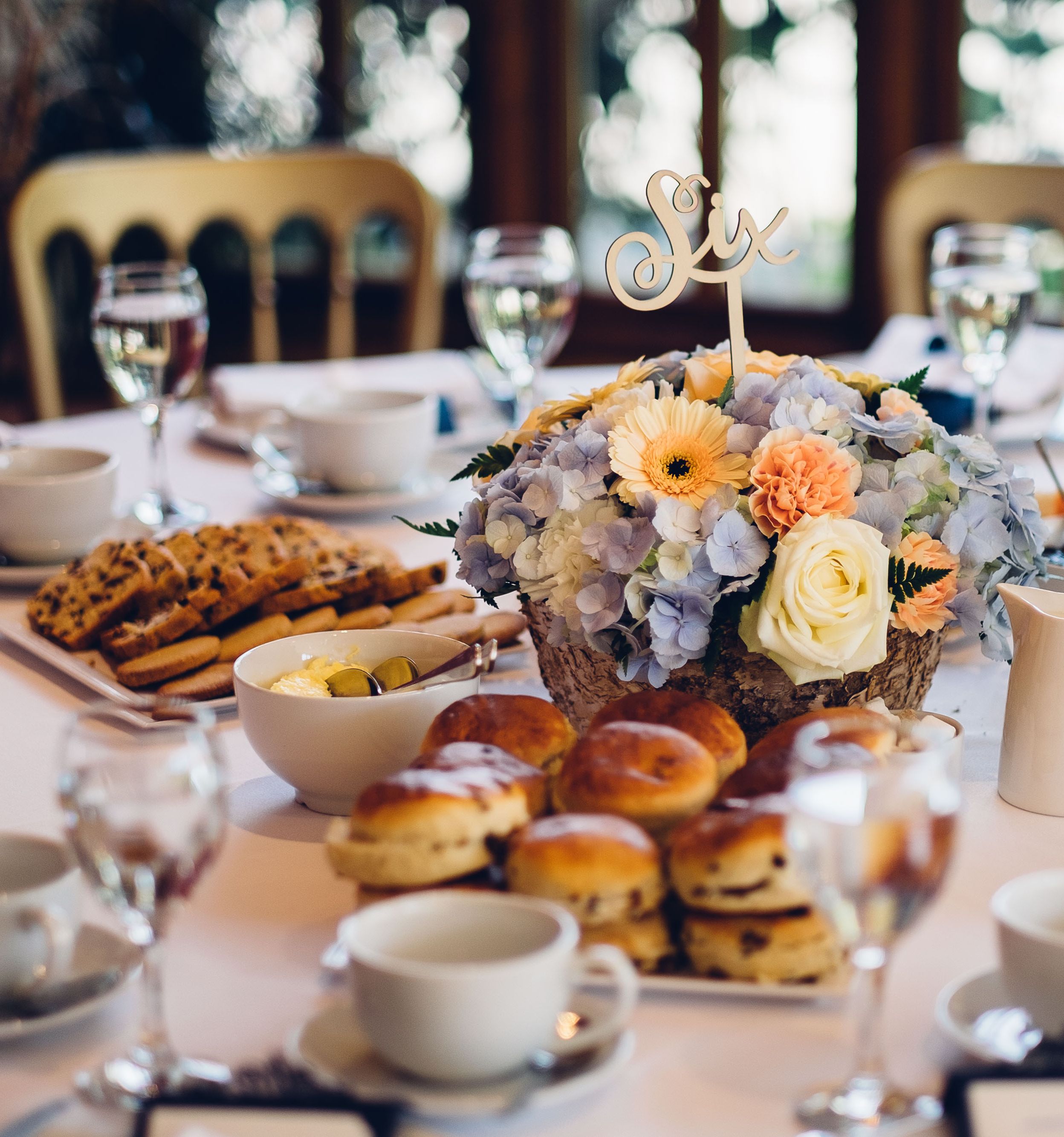 A close-up of a table set for afternoon tea with scones, cookies, and various spreads.