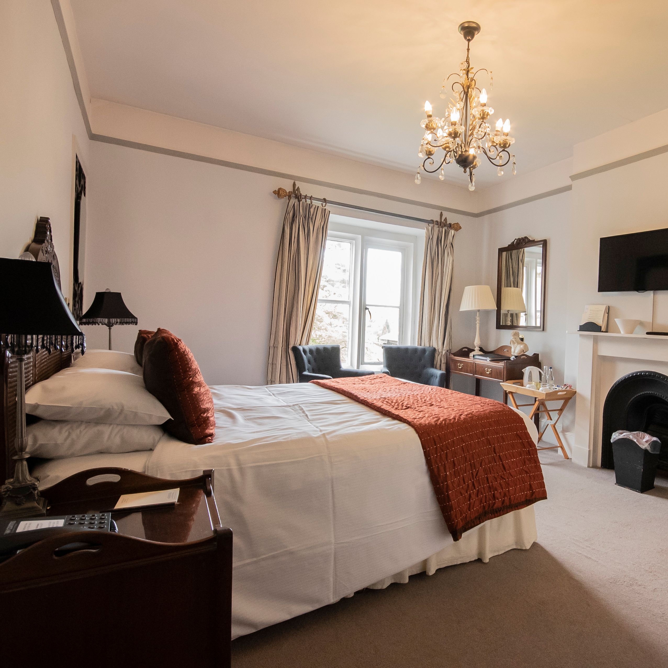 Bedroom with statement fireplace and chandelier