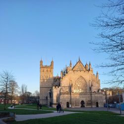 Exeter Cathedral at sunset with people walking across Cathedral Green in Exeter, Devon