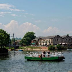 Two people on a green ferry boat crossing the River Exe at Exeter Quayside on a sunny da