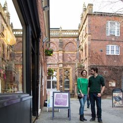 Couple walking down Gandy Street in Exeter, lined with independent shops and historic red-brick buildings