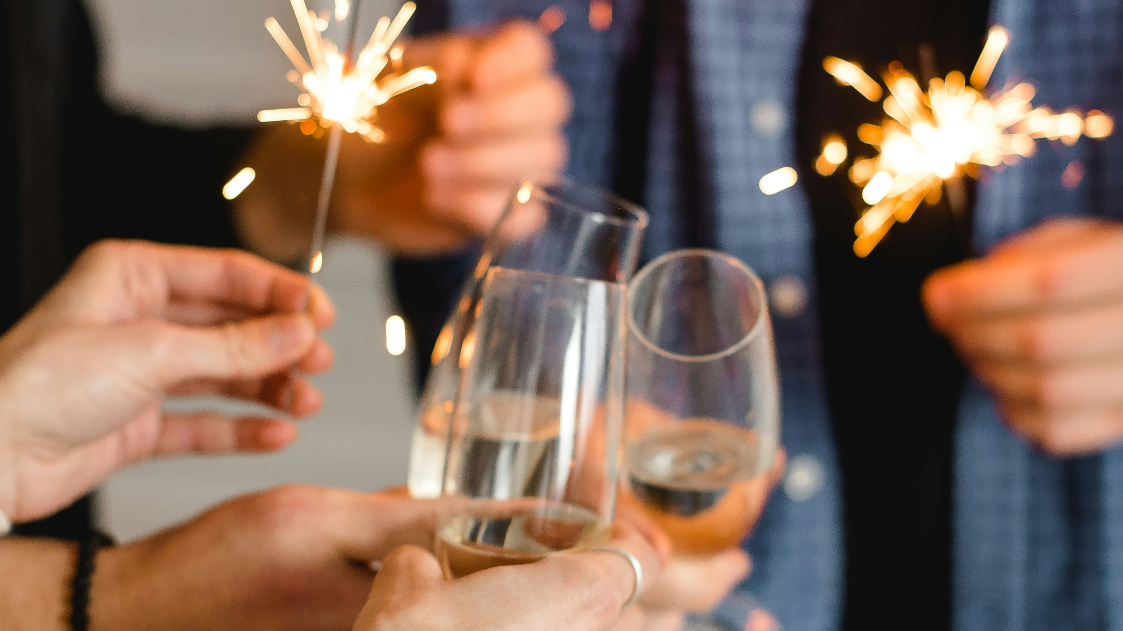 People holding sparklers and glasses of champagne, celebrating together.