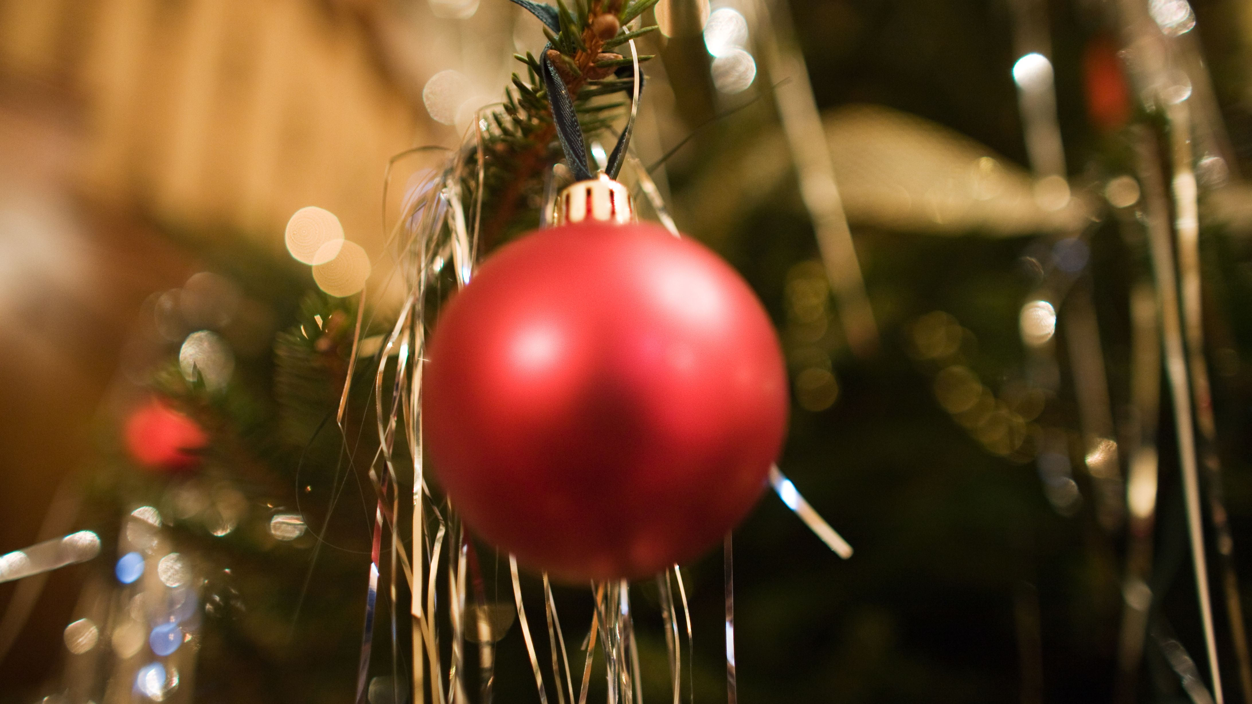 Red Christmas bauble hanging on a decorated tree with tinsel