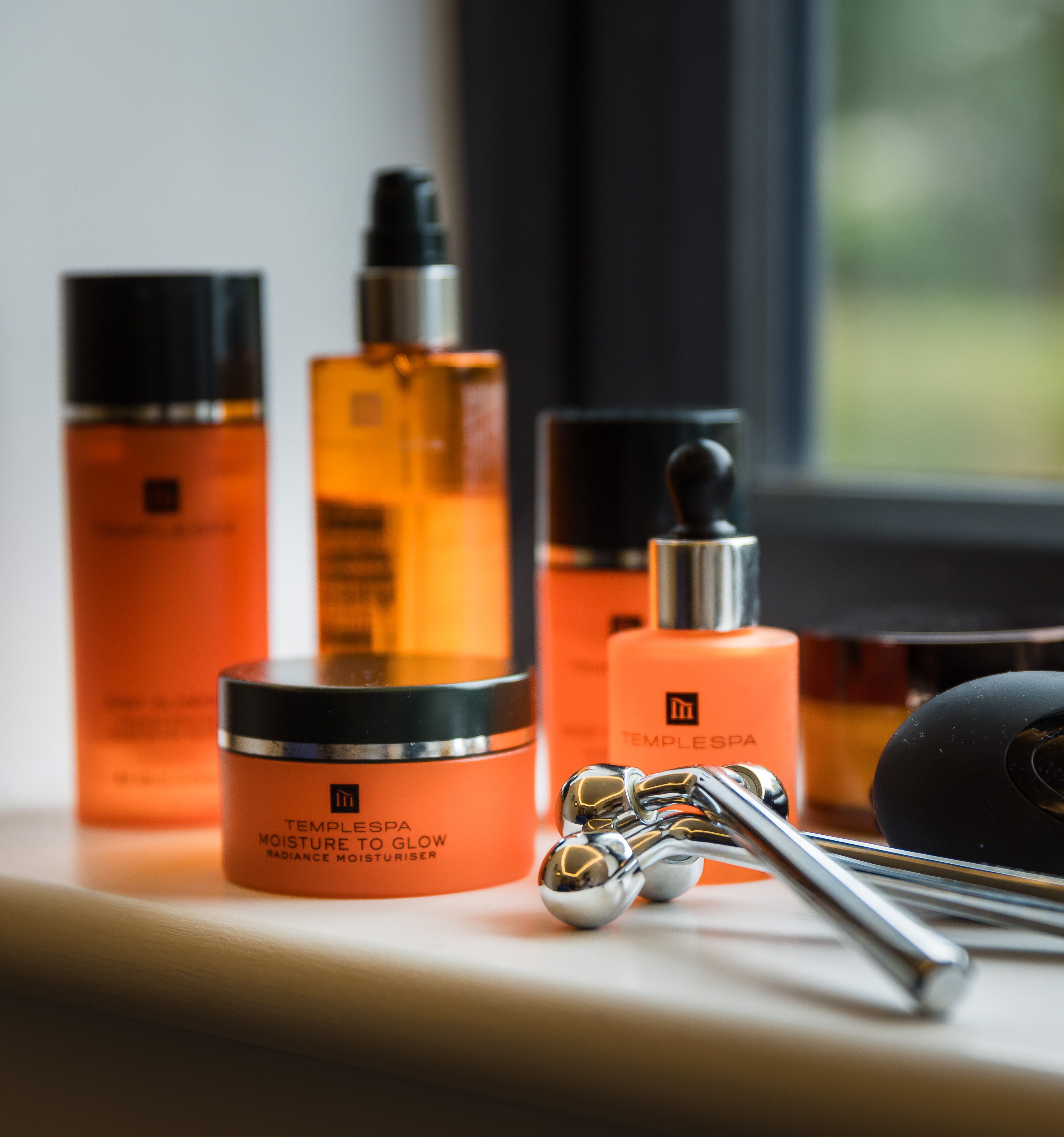 Temple Spa skincare products and facial rollers arranged on a windowsill.