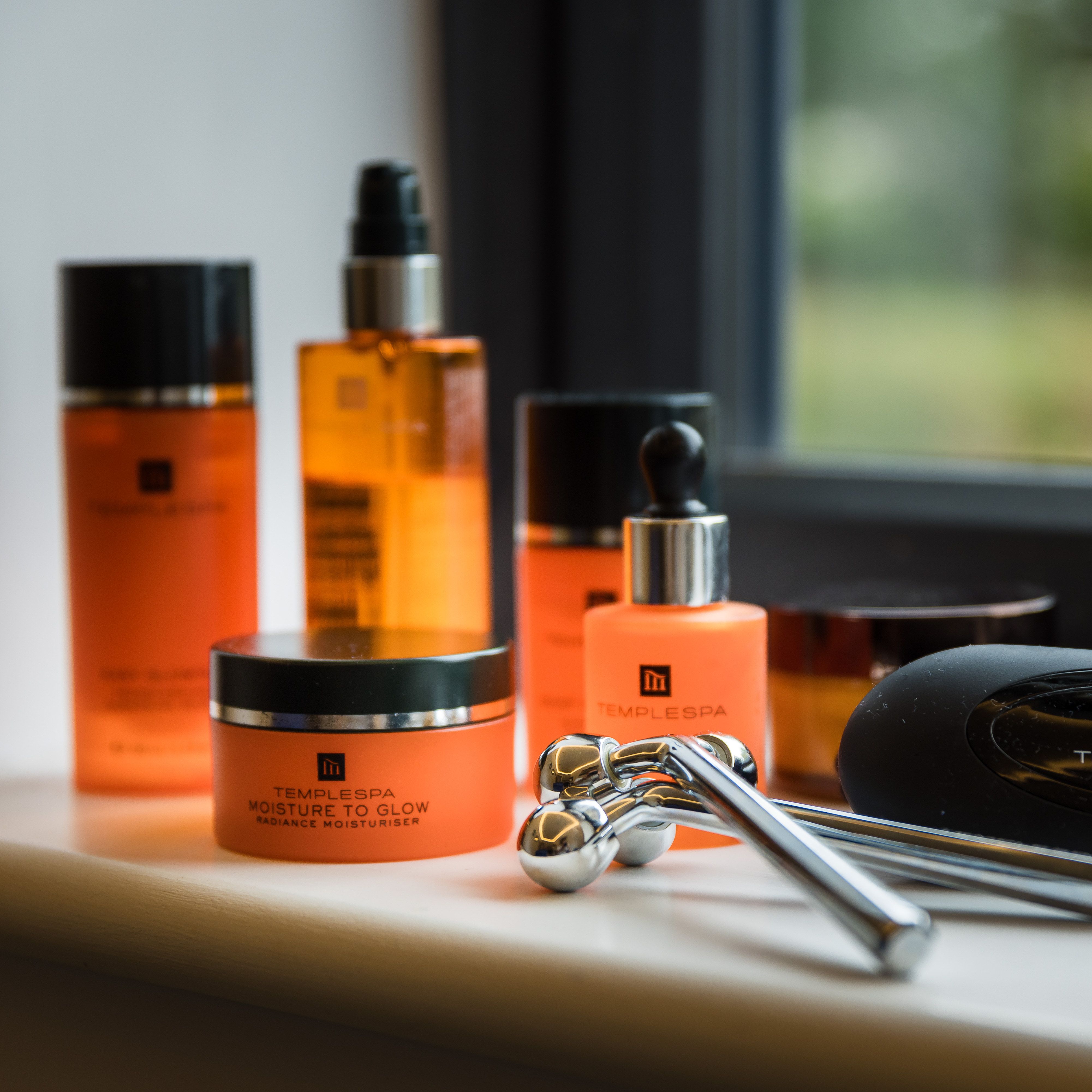 Temple Spa skincare products and facial rollers arranged on a windowsill.
