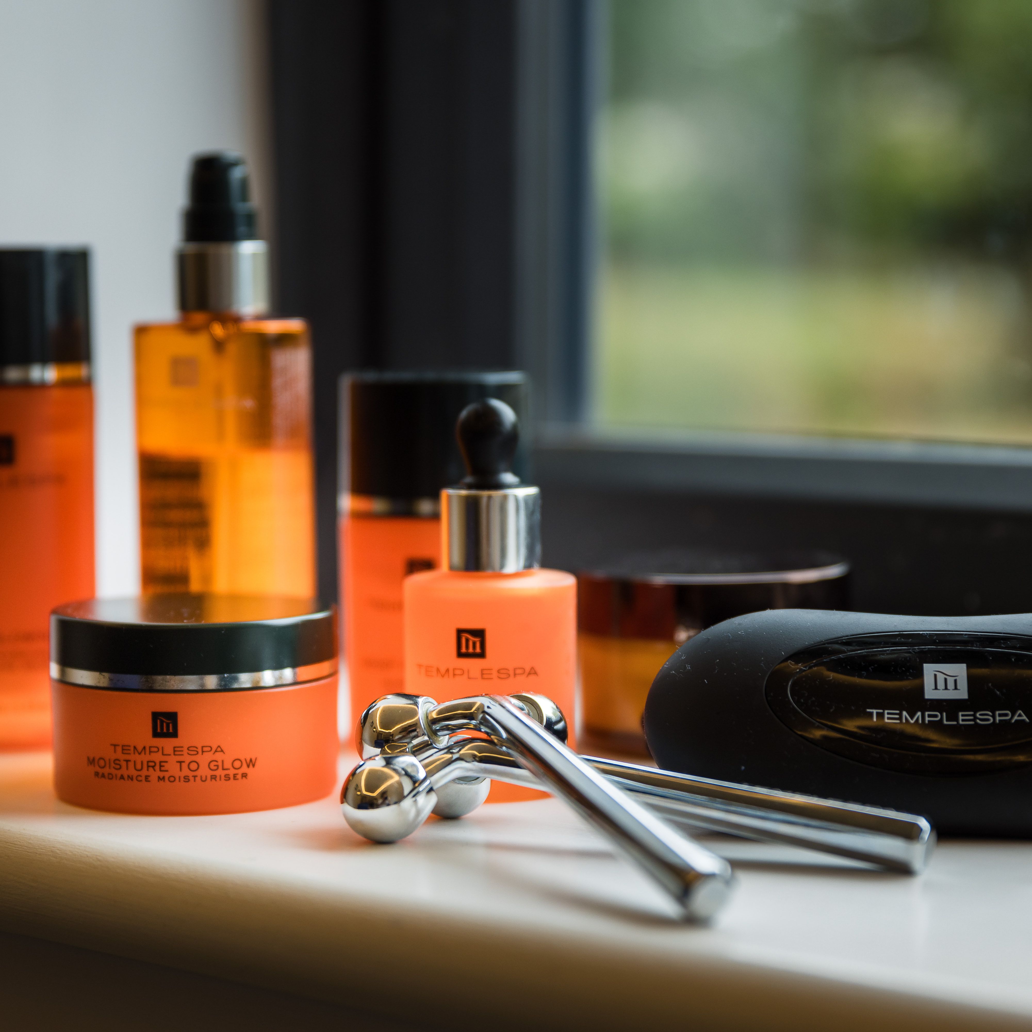 Temple Spa skincare products and facial rollers arranged on a windowsill.