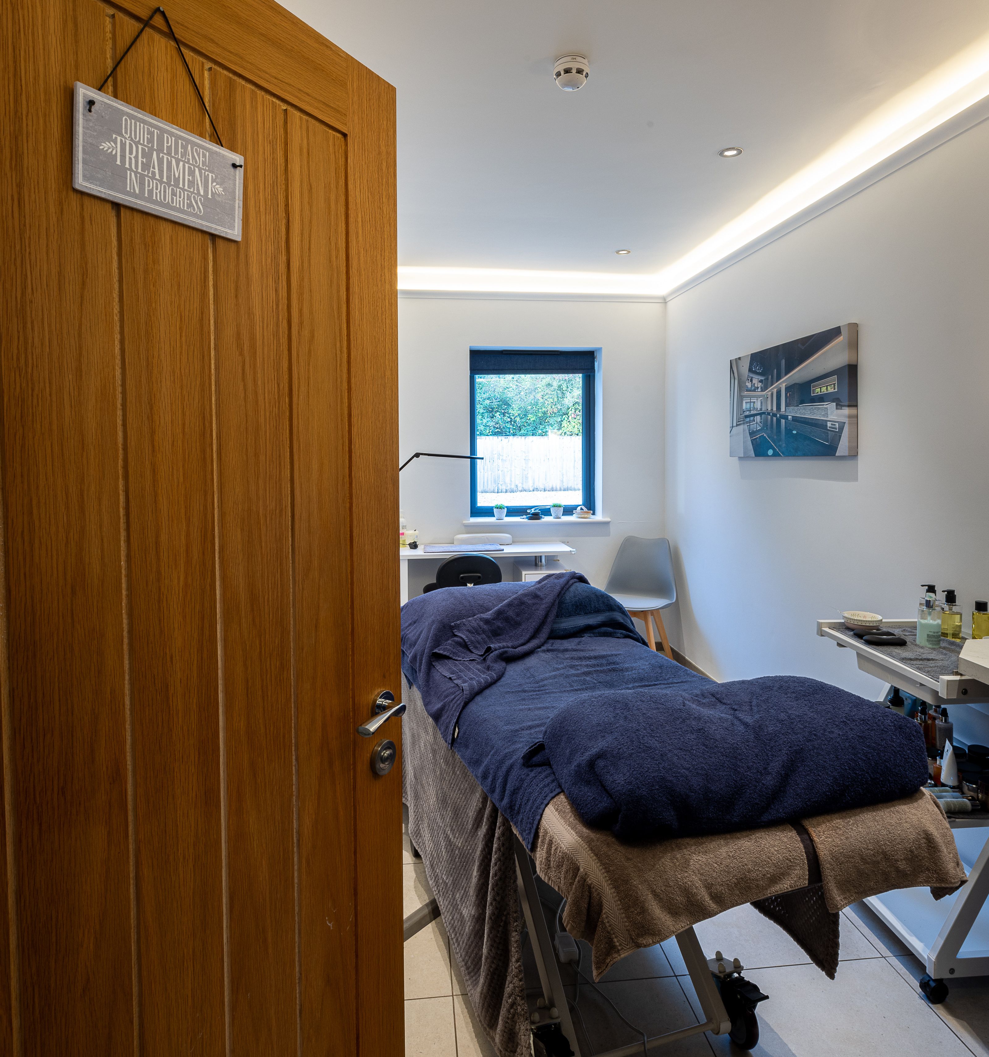 A cozy treatment room with a massage table and a sign on the door reading 'Quiet Please, Treatment in Progress.'