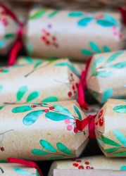 Close-up of decorative Christmas crackers with green leaves and red berries