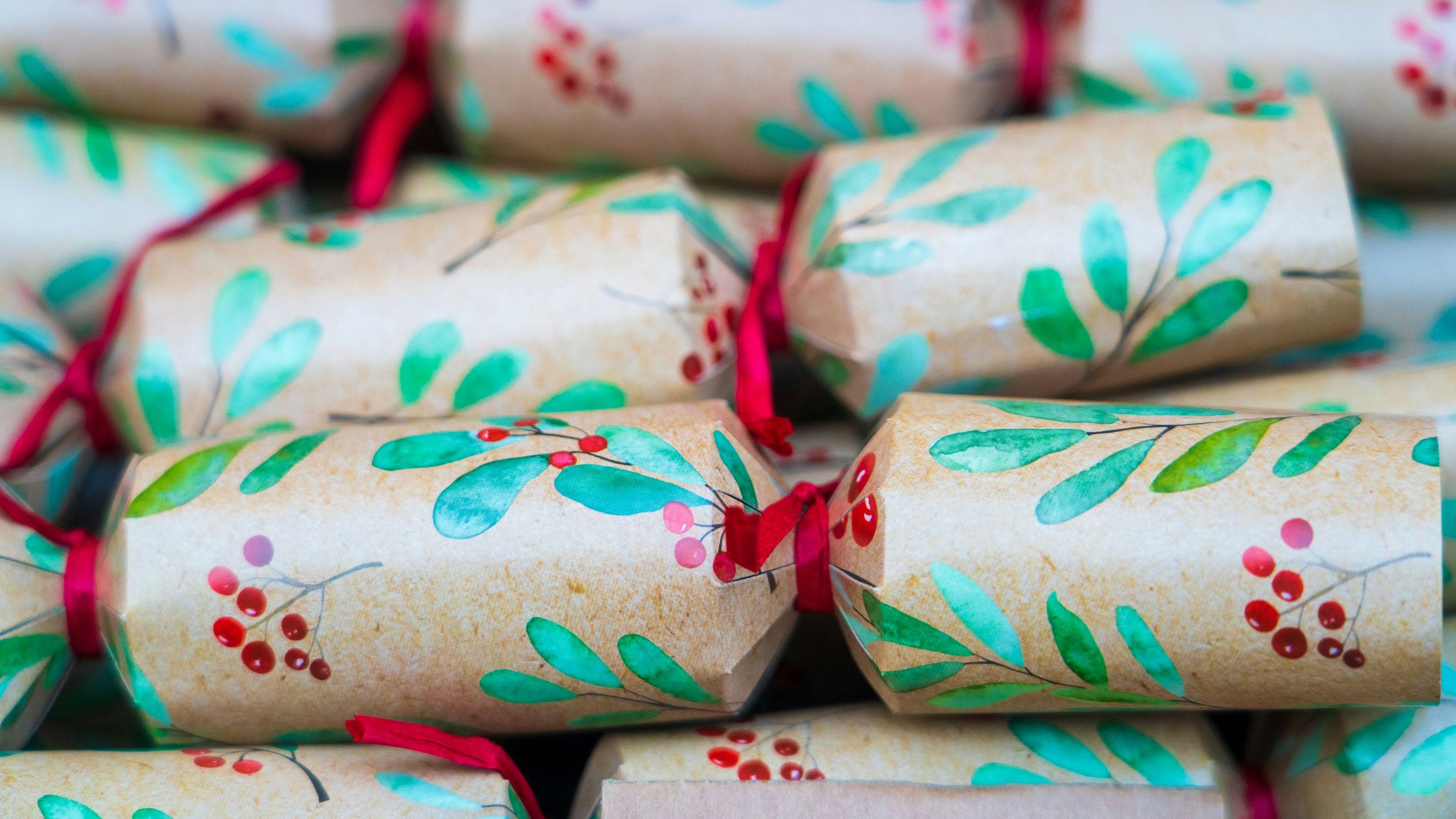 Close-up of decorative Christmas crackers with green leaves and red berries
