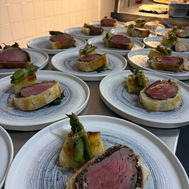 Plates of beef Wellington served with roasted potatoes and asparagus in a restaurant kitchen