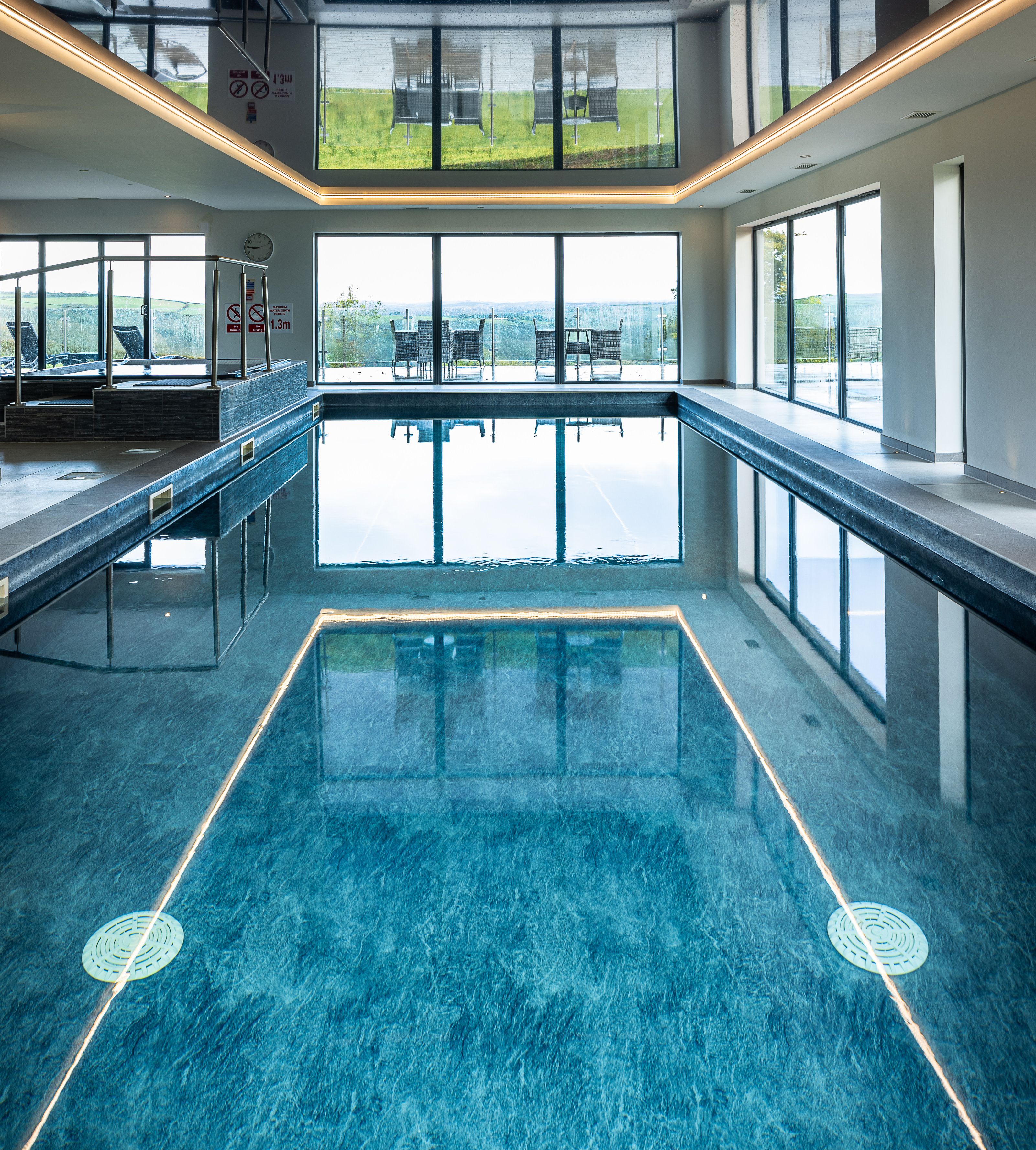 Indoor swimming pool with large windows and outdoor seating visible.