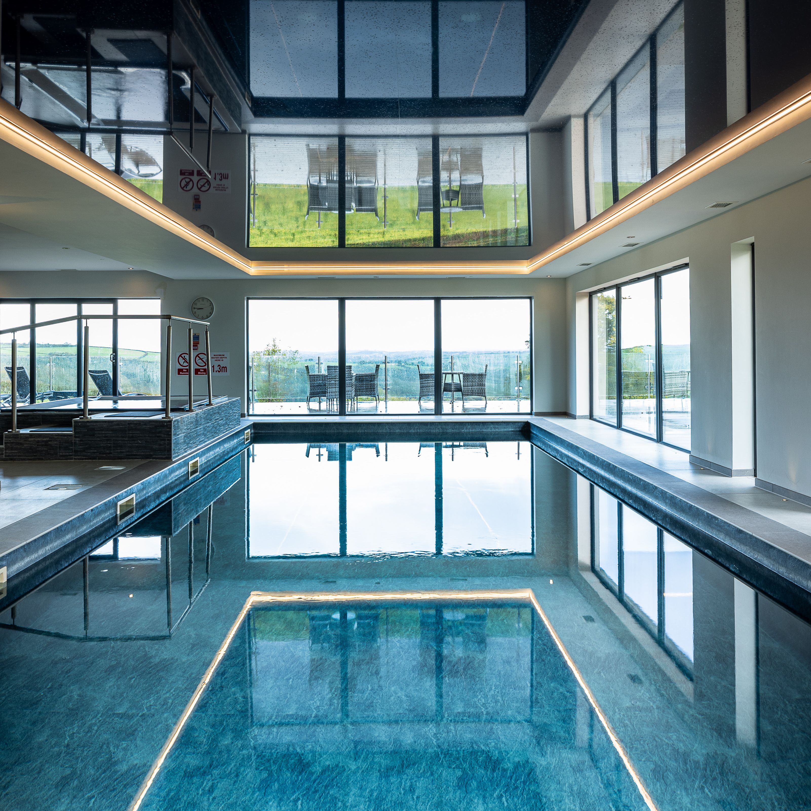 Indoor swimming pool with large windows and outdoor seating visible.