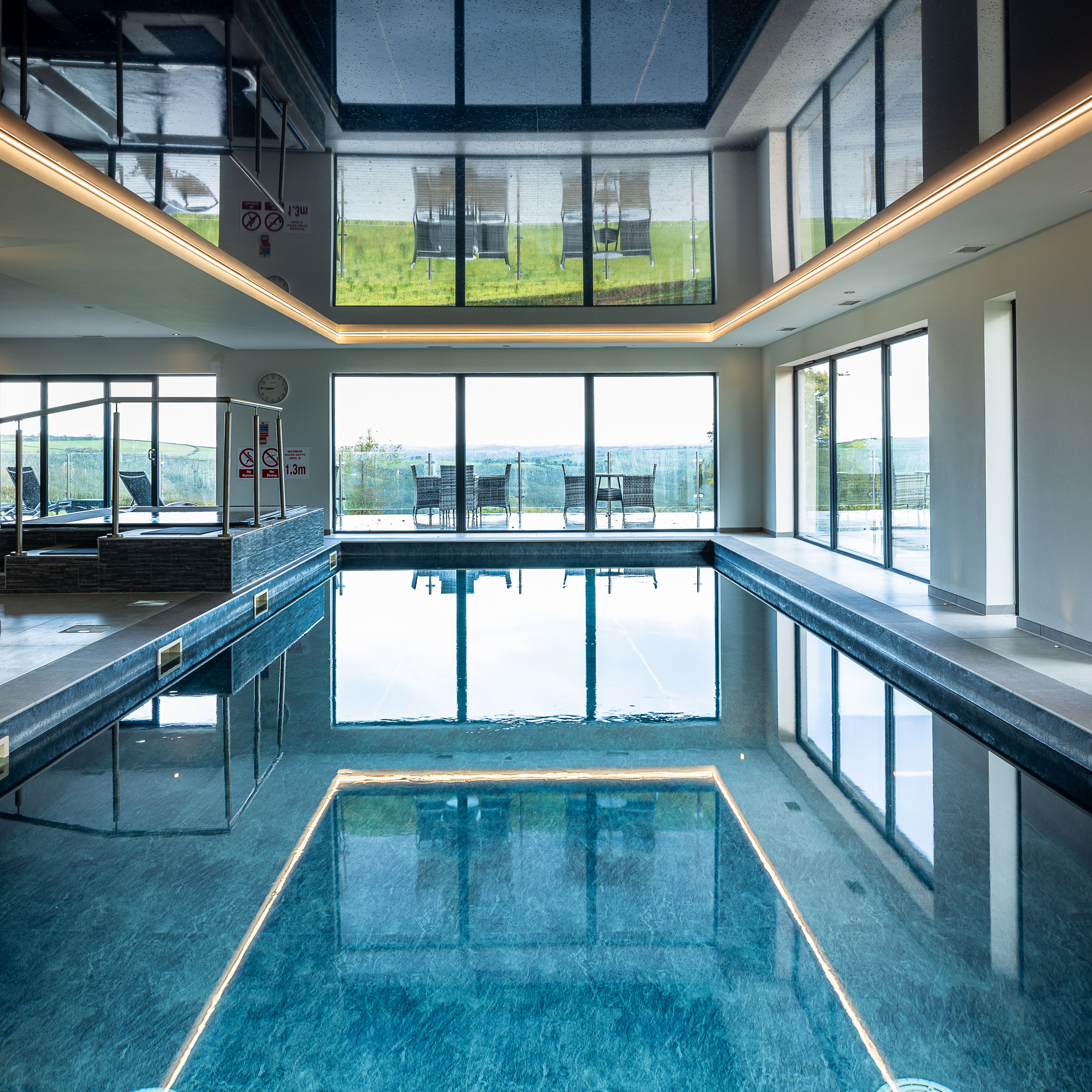 Indoor swimming pool with large windows and outdoor seating visible.