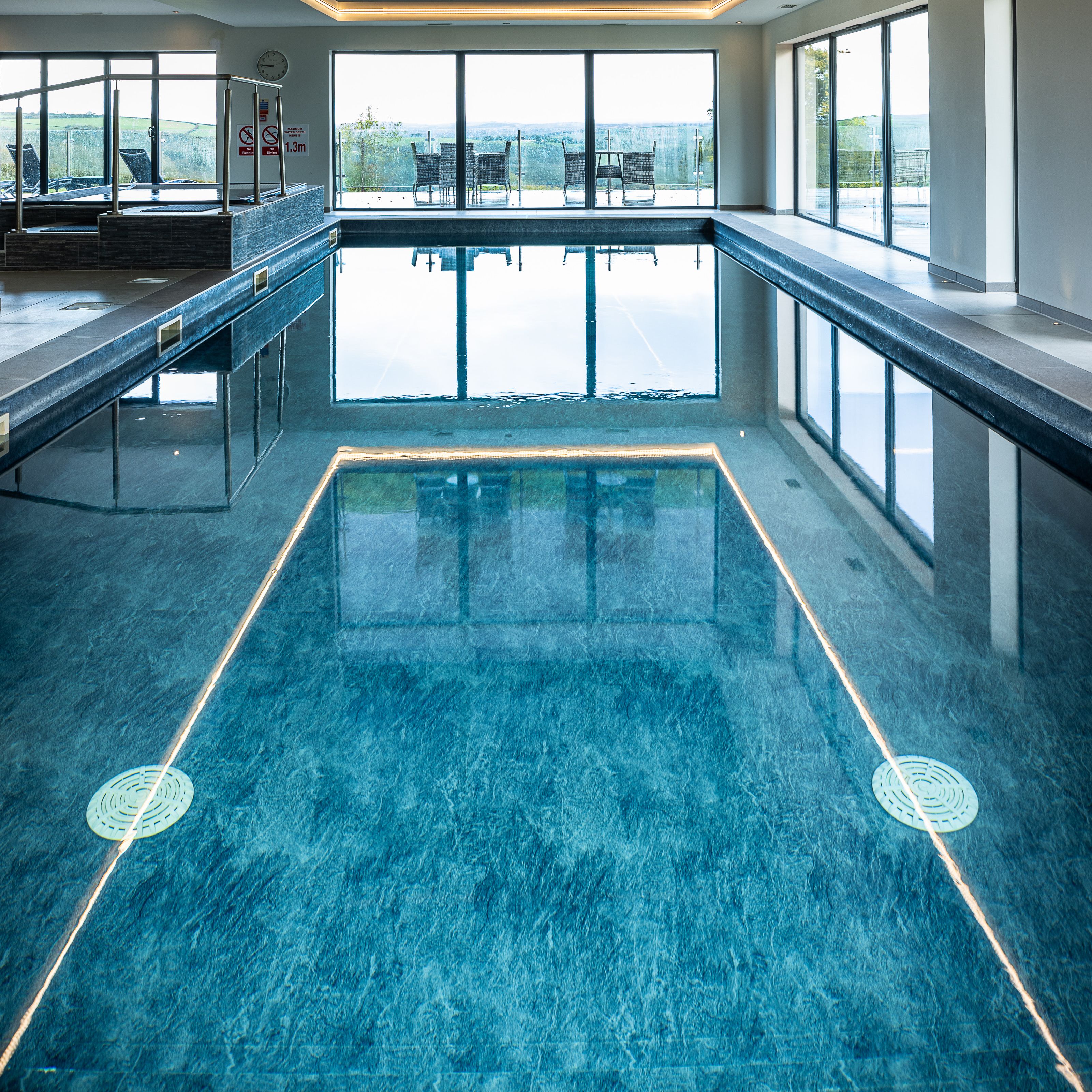 Indoor swimming pool with large windows and outdoor seating visible.