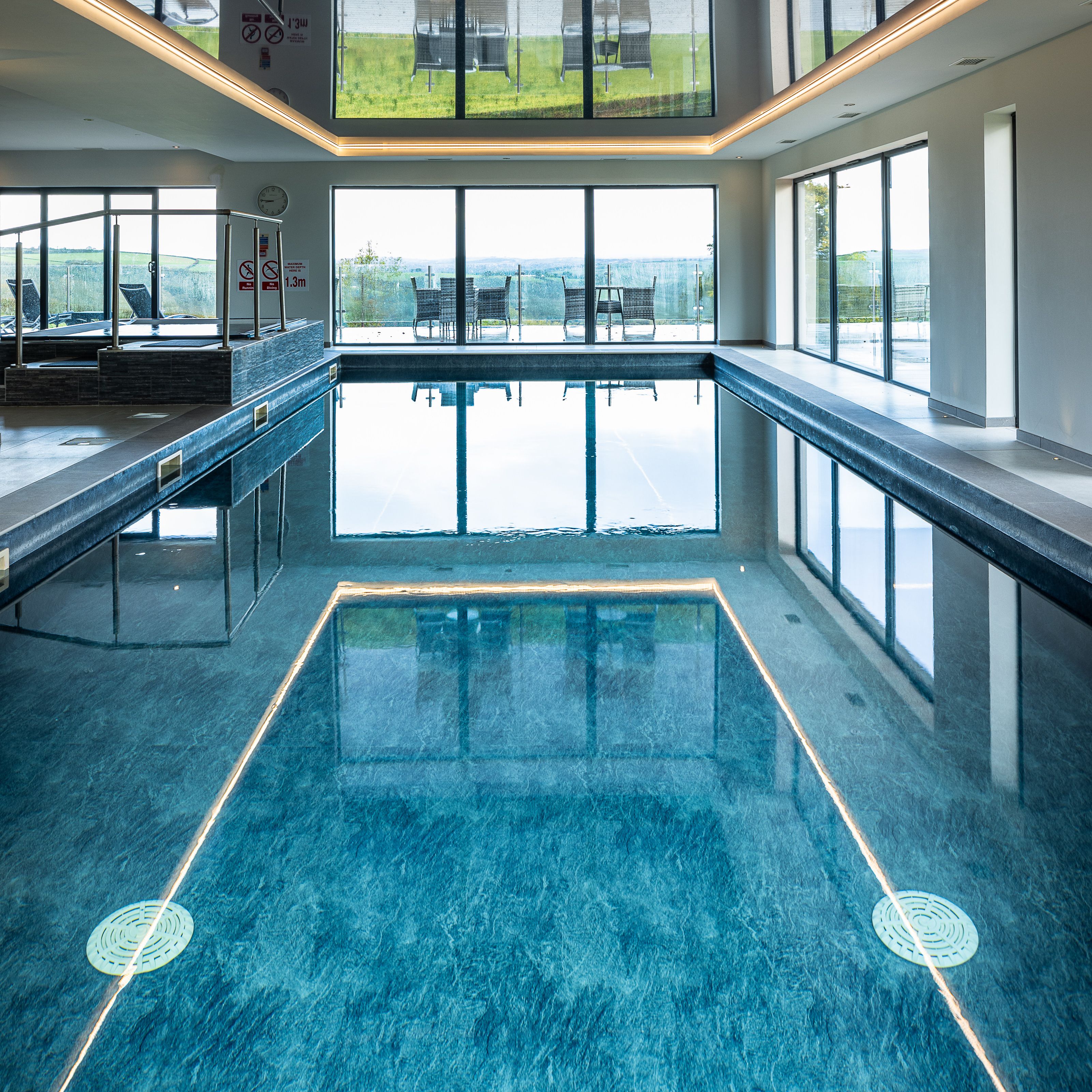 Indoor swimming pool with large windows and outdoor seating visible.