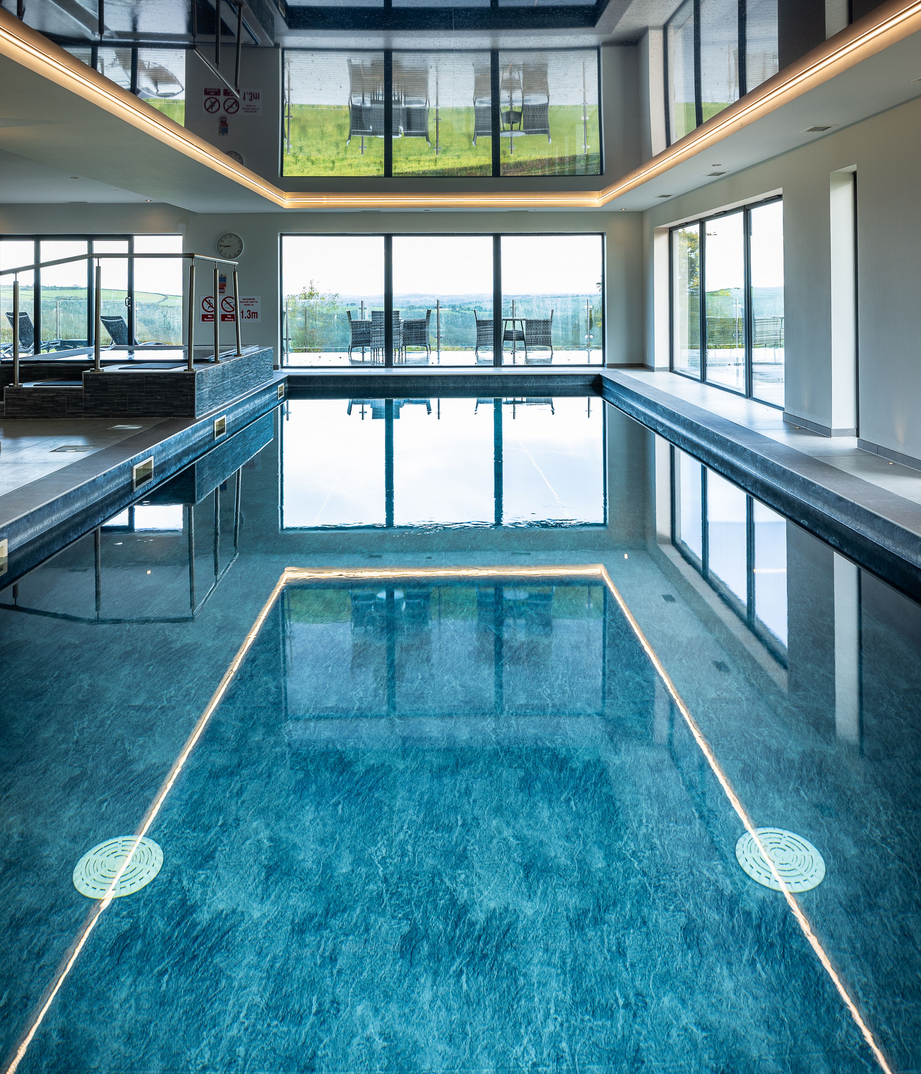 Indoor swimming pool with large windows and outdoor seating visible.