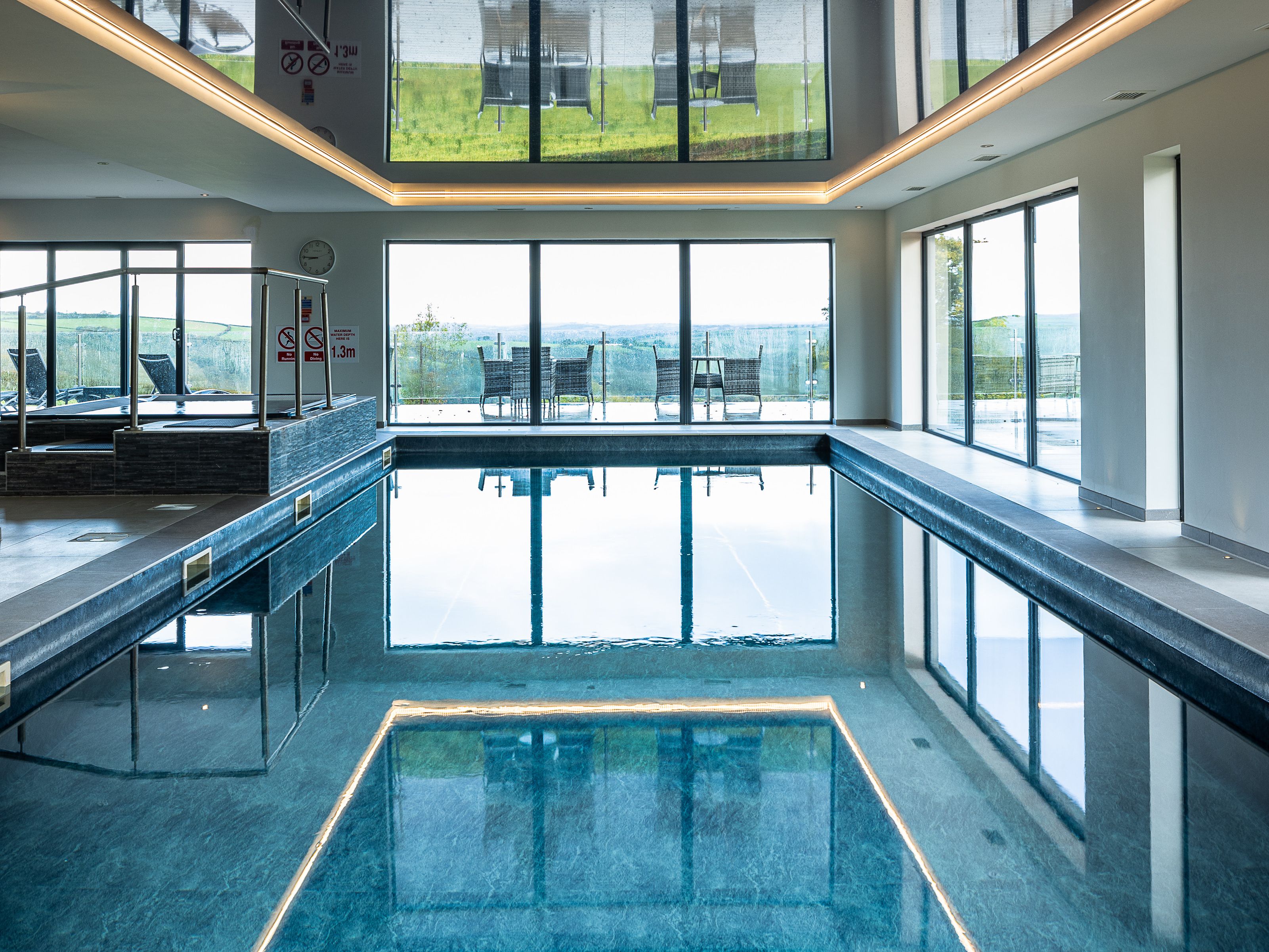 Indoor swimming pool with large windows and outdoor seating visible.