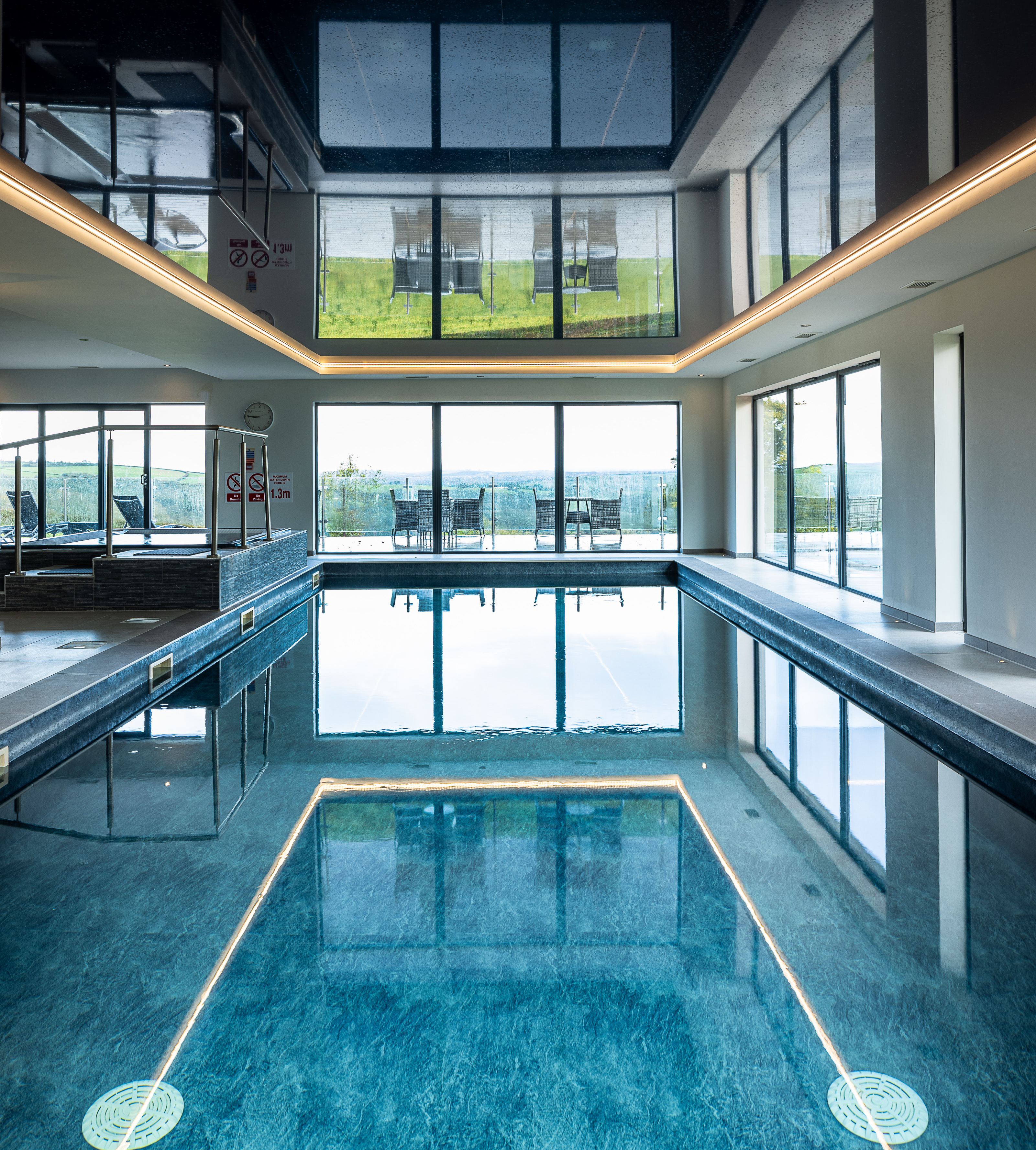 Indoor swimming pool with large windows and outdoor seating visible.