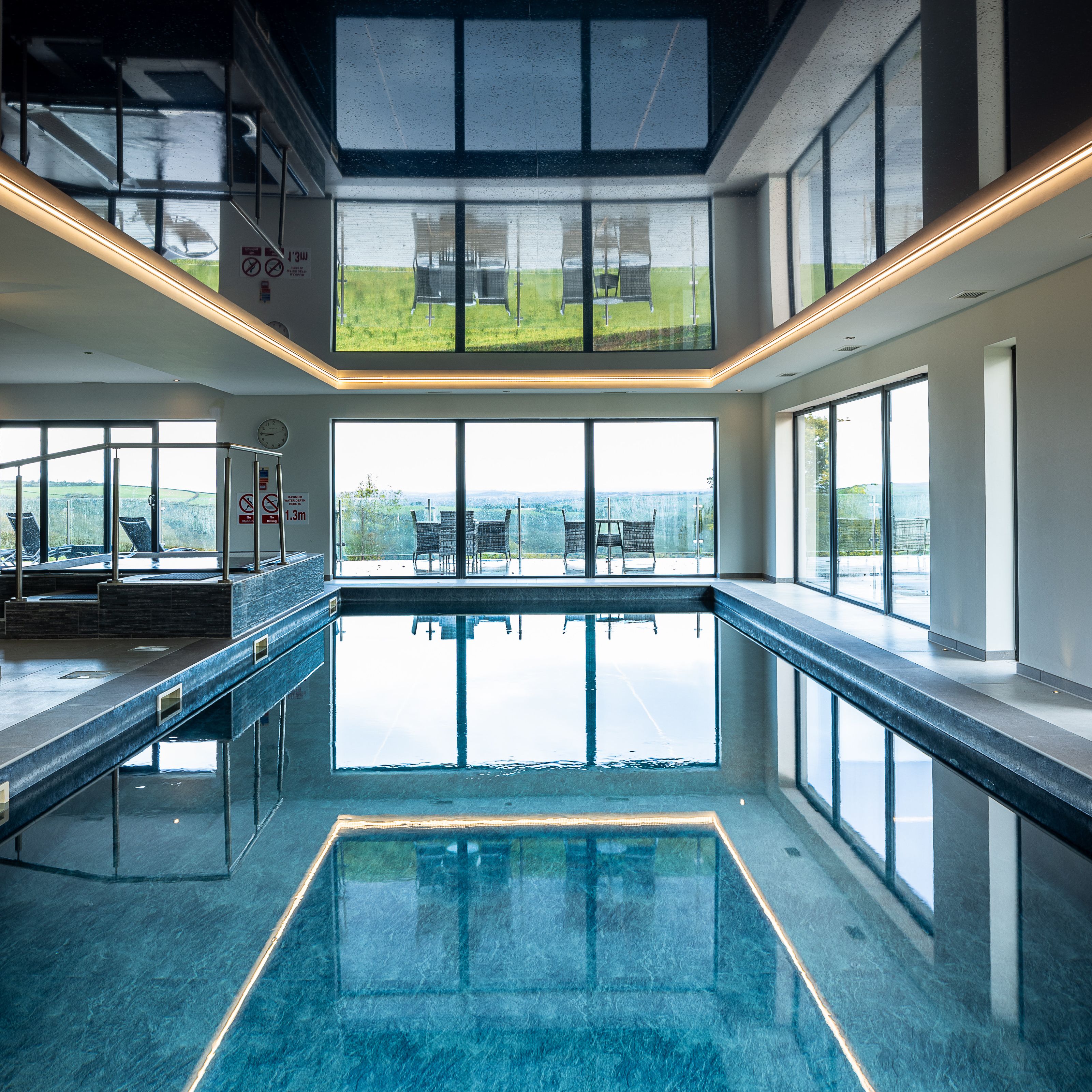 Indoor swimming pool with large windows and outdoor seating visible.