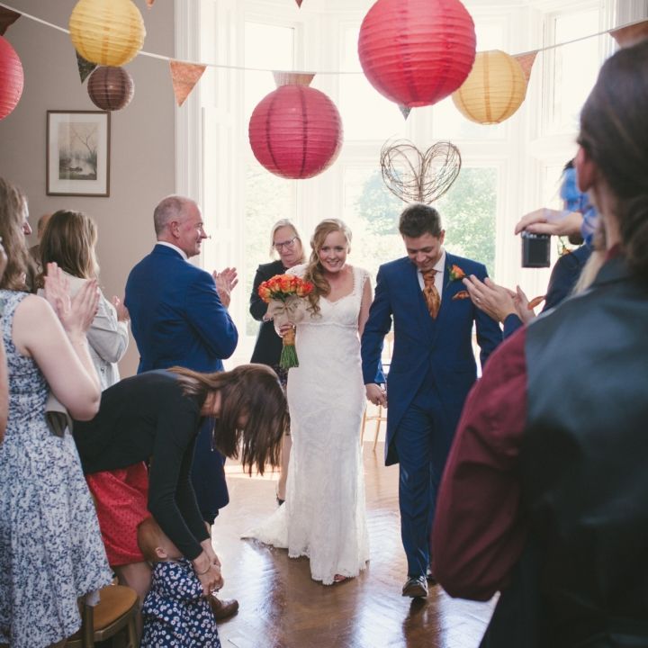 Bride and groom walking down the aisle after their wedding ceremony with guests applauding around them