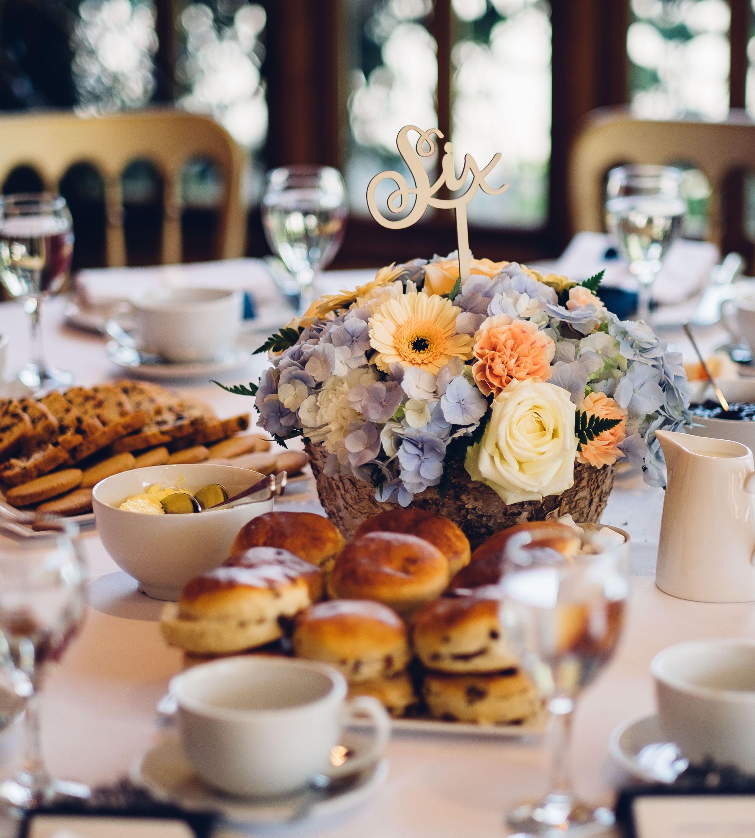 Elegant wedding table setting with flower centerpiece, pastries, and tea