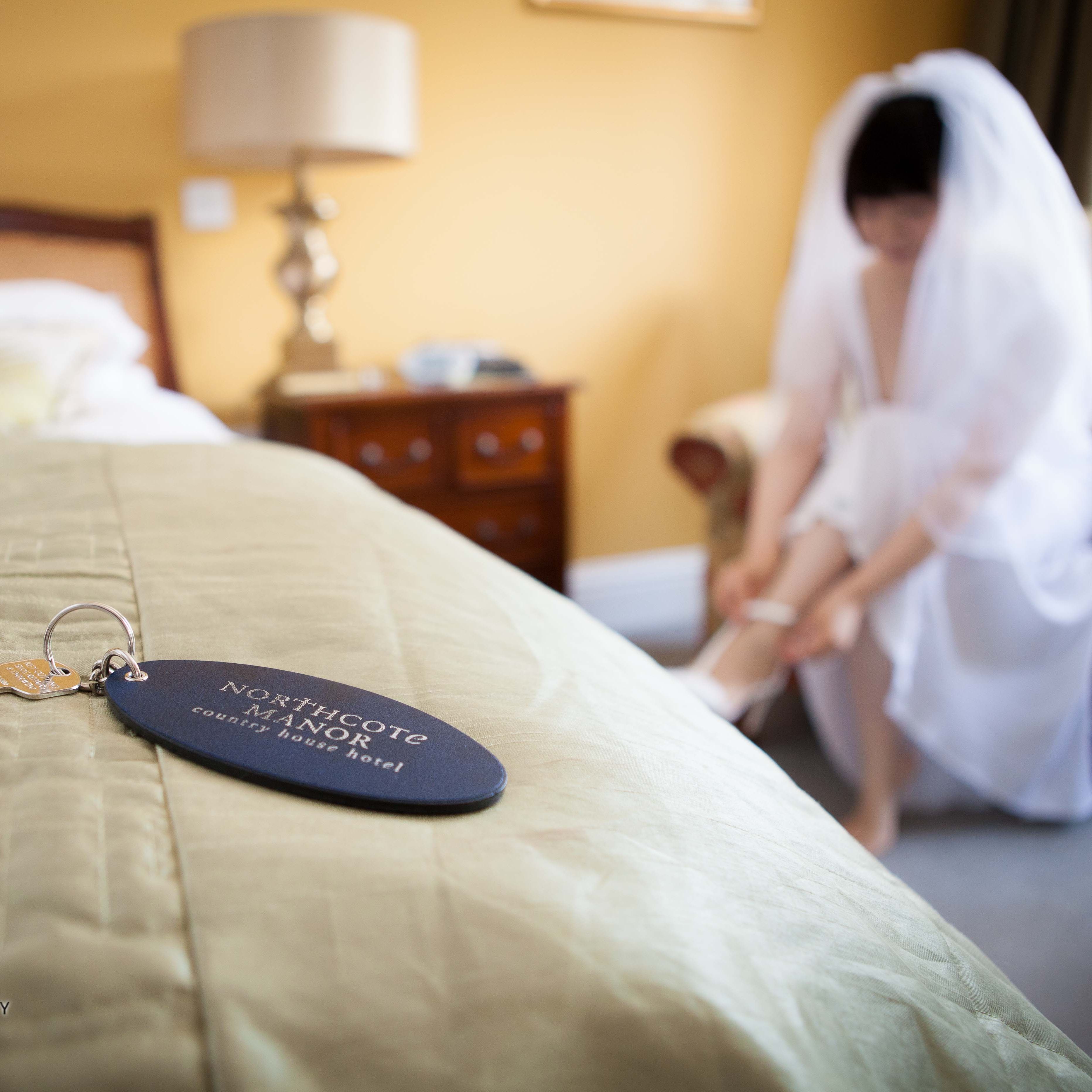 Room key on bed with bride in background getting ready