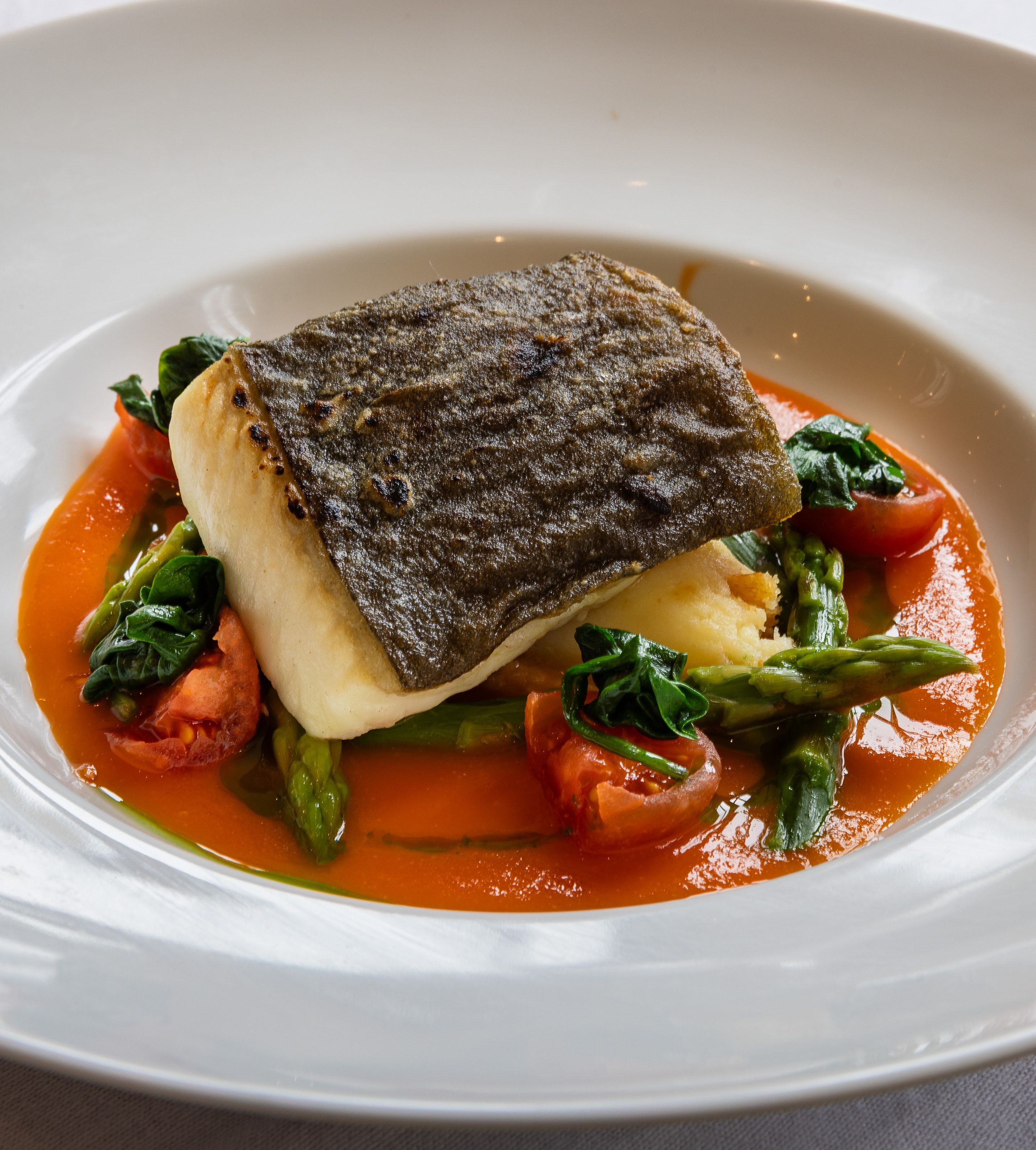 Plated seared fish fillet with vegetables and sauce