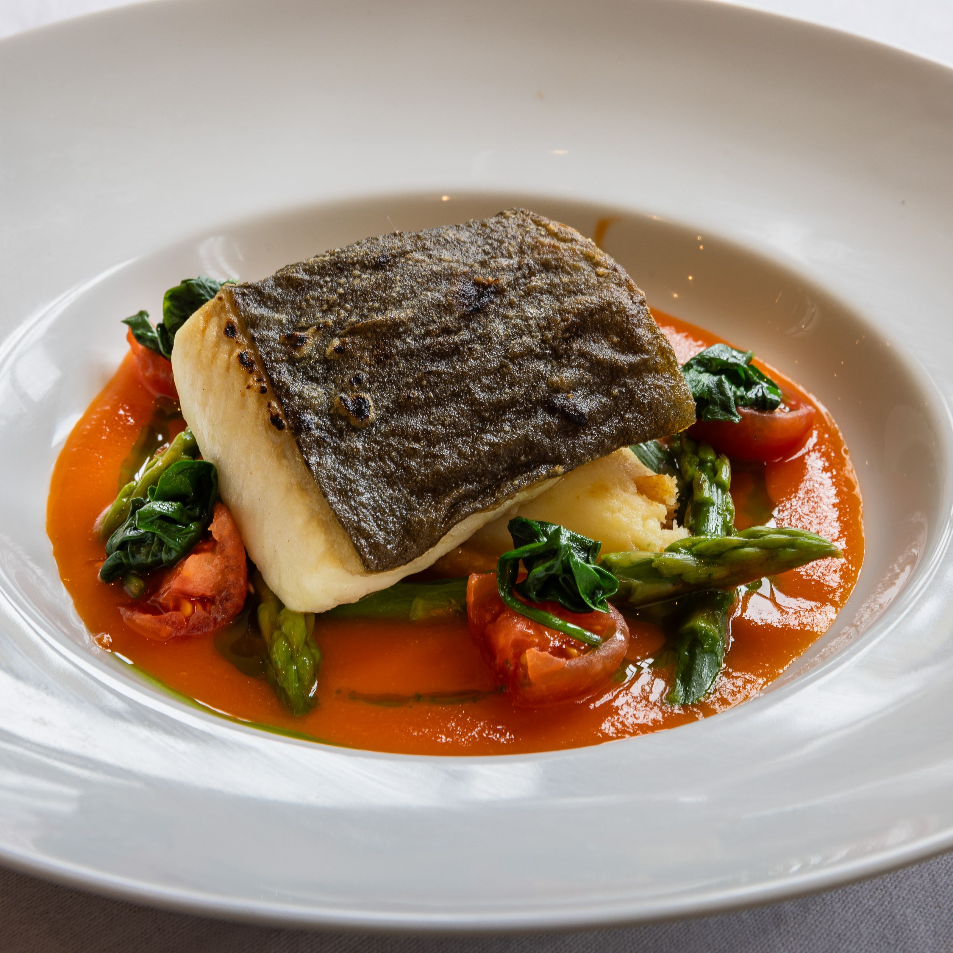 Plated seared fish fillet with vegetables and sauce