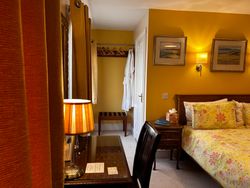 Side of bed in Bedroom 1, dressing table and chair, hanging space, luggage rack, robes and door to ensuite