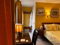 Side of bed in Bedroom 1, dressing table and chair, hanging space, luggage rack, robes and door to ensuite