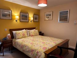 Kingsize bed of Bedroom 1with bedside tables, lights and pictures