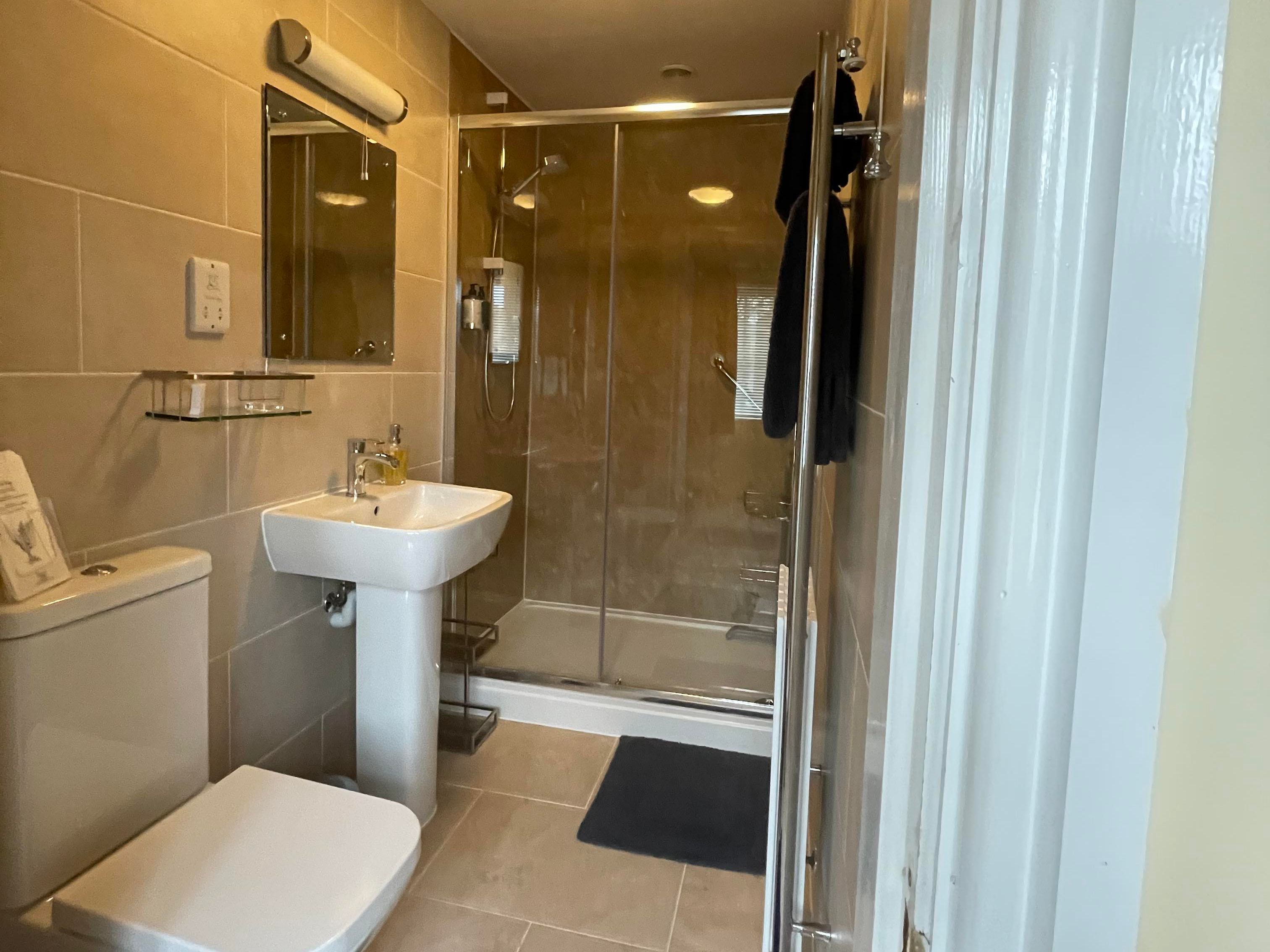 Shower, wash basin, mirror toilet and towel rail in the en-suite of Bedroom 1