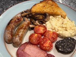 Two plates of full english breakfasts with eggs, sausages, black pudding, bacon,tomatoes, mushrooms and fried bread