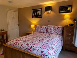 Double bed, side tables, lights, pictures and door of Bedroom 2