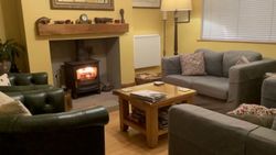 Cozy living room with a wood-burning stove, sofas, coffee table, and warm yellow walls.