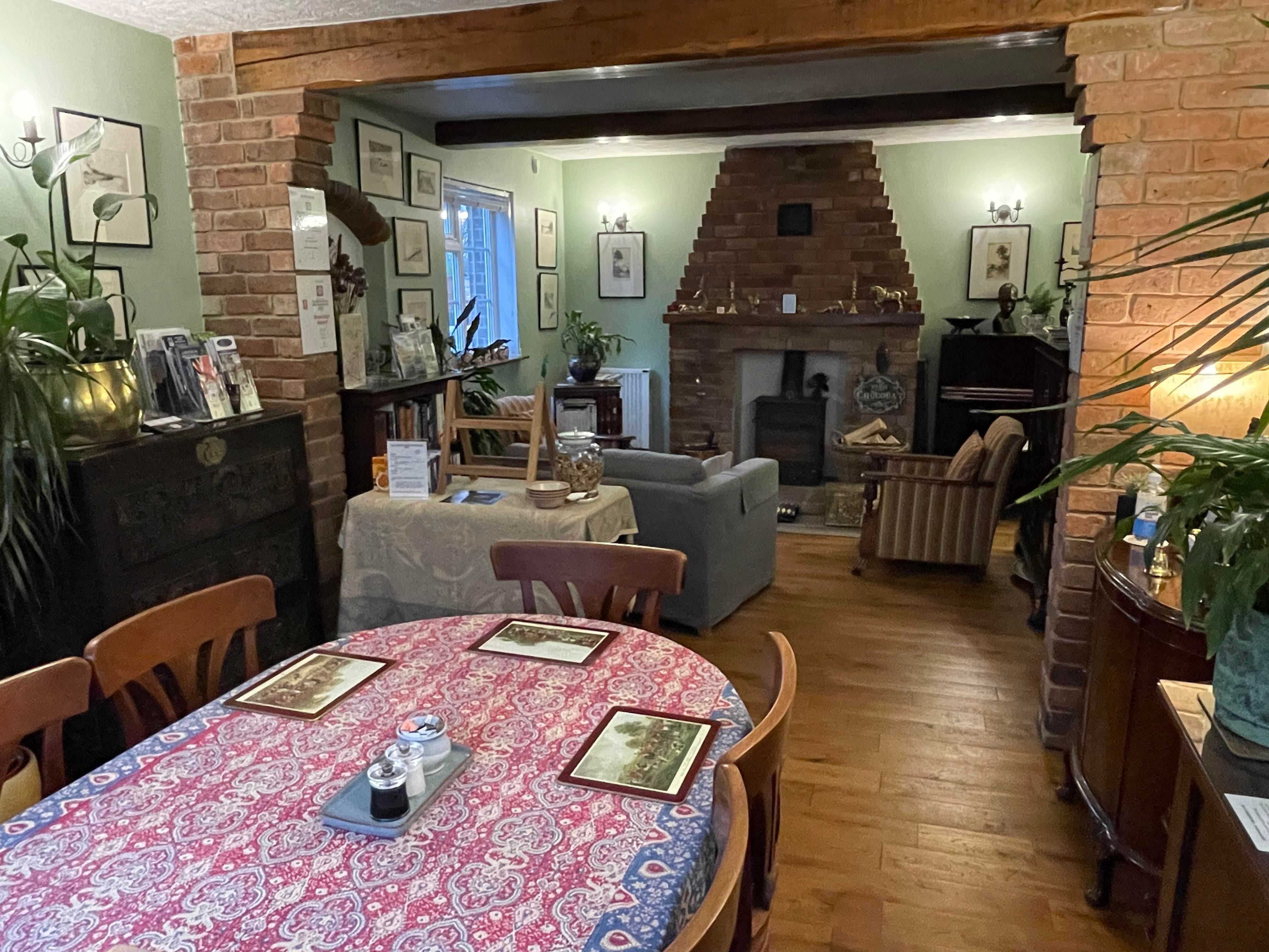 View of the Dining Room from the end of the room with the window at the front of the house -  Dining Table, comfy seating for guests and plants