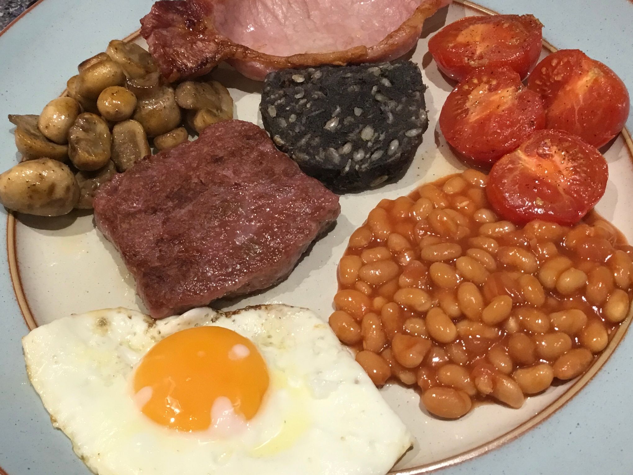 Fried Egg, homemade beef sausage slice, bacon, black pudding, mushrooms, tomatoes and baked beans