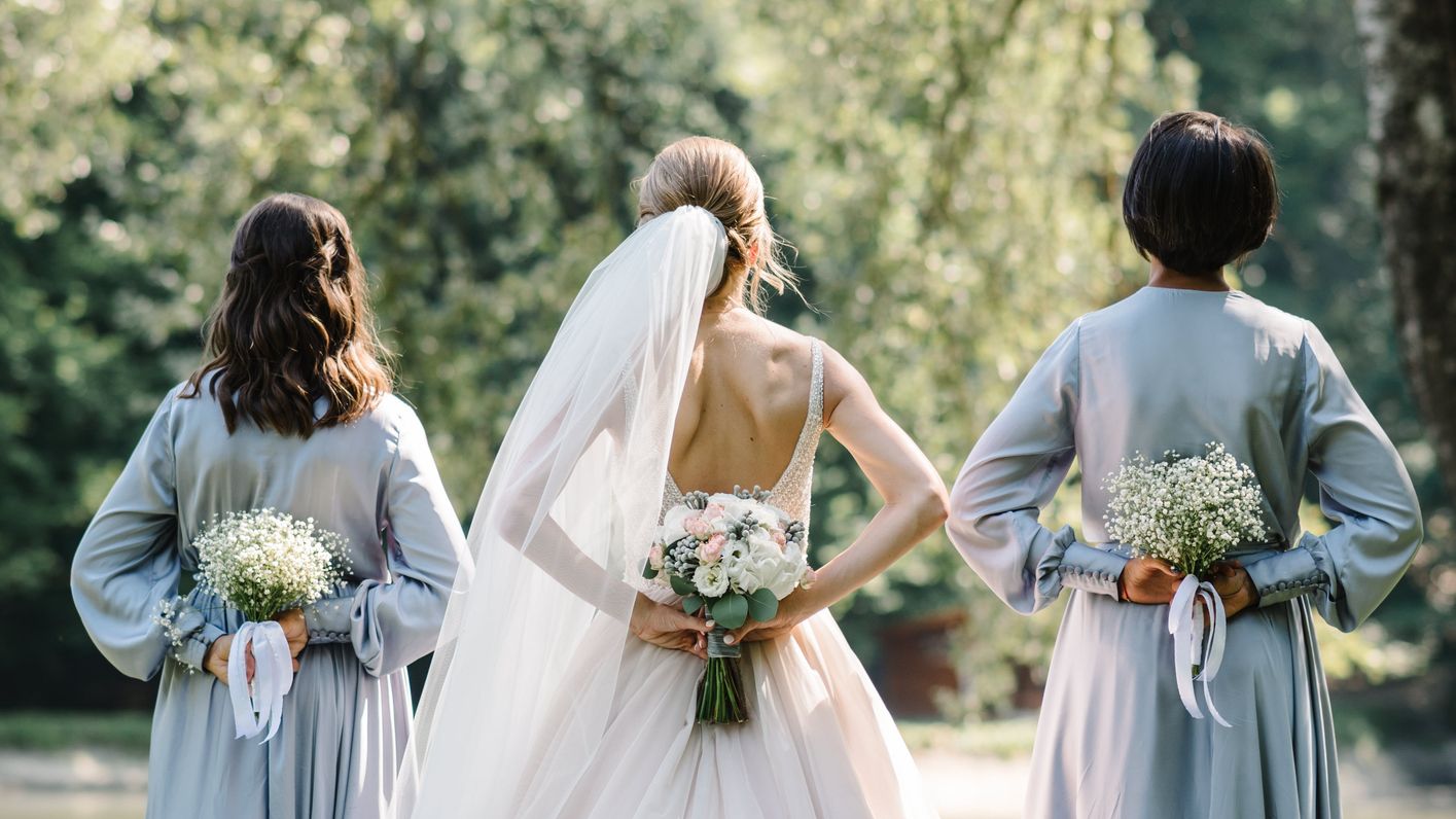 Bride standing with her bridesmaids with bouquets behind their backs