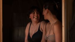 Two women in swimsuits sitting and smiling together inside an Iglusauna.