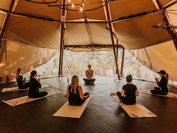 Group of people practicing yoga inside a tipi tent