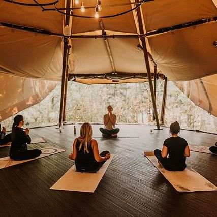 Group of people practicing yoga inside a tipi tent