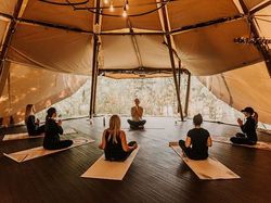 Group of people practicing yoga inside a tipi tent