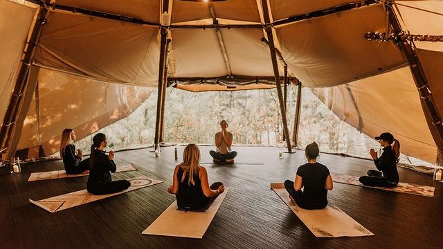 Group of people practicing yoga inside a tipi tent