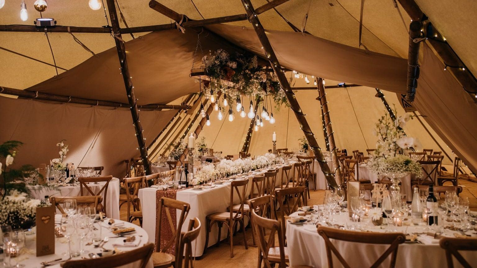Elegant wedding reception setup inside a decorated tipi tent