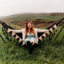 Woman sitting on a hammock decorated with a 'Just Married' banner in a grassy field