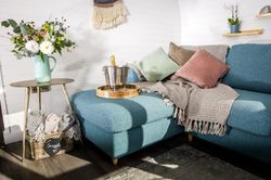 Living area with with vase of flowers, and bucket with champagne on sofa