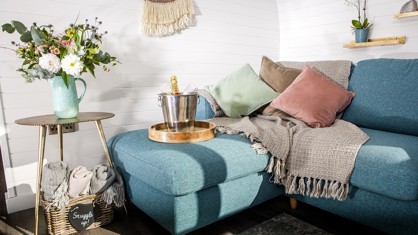 Living area with with vase of flowers, and bucket with champagne on sofa