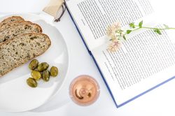 Plate of bread and olives with book and glass of wine